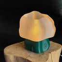 Forest-green Studio.LUNA L001 lamp switched on, standing on a wooden tree-stump side table