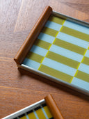 Close-up of the Hygge serving tray by cont., pale blue and golden-ochre glass with an oak handle